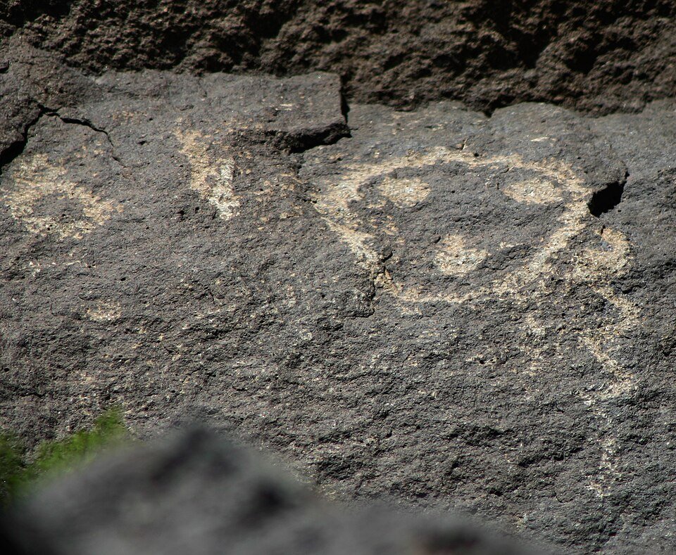 Un petroglifo de contorno redondo, parecido a un rostro, grabado en basalto oscuro