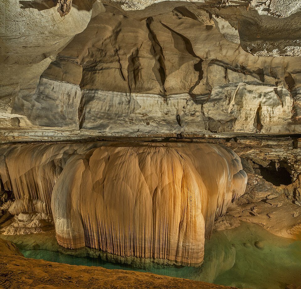 La Giant Flowstone de Blanchard Springs Caverns, una cortina de roca acanalada sobre una poza verde