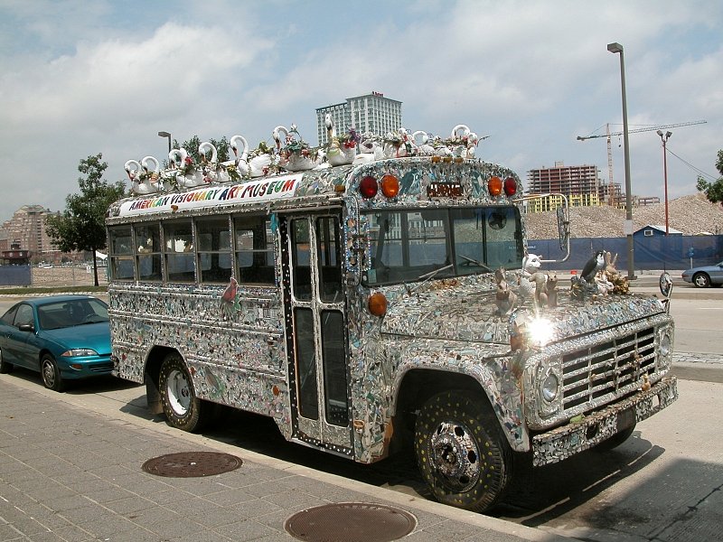 A bus covered in mosaic and topped with white swans, painted with the museum's name