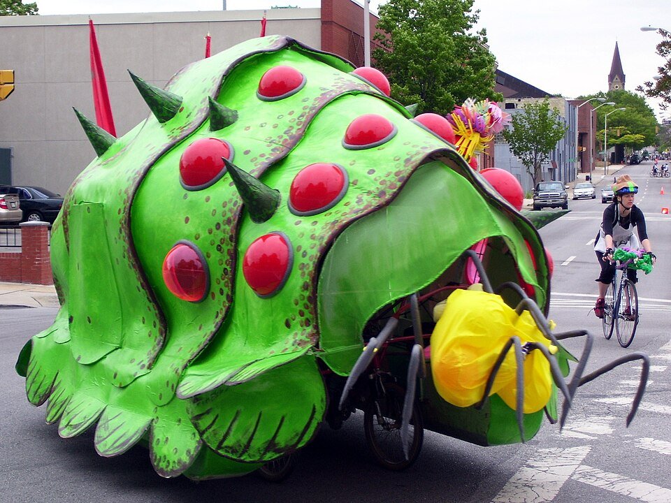A giant green creature on wheels, a kinetic sculpture, rolling down a Baltimore street