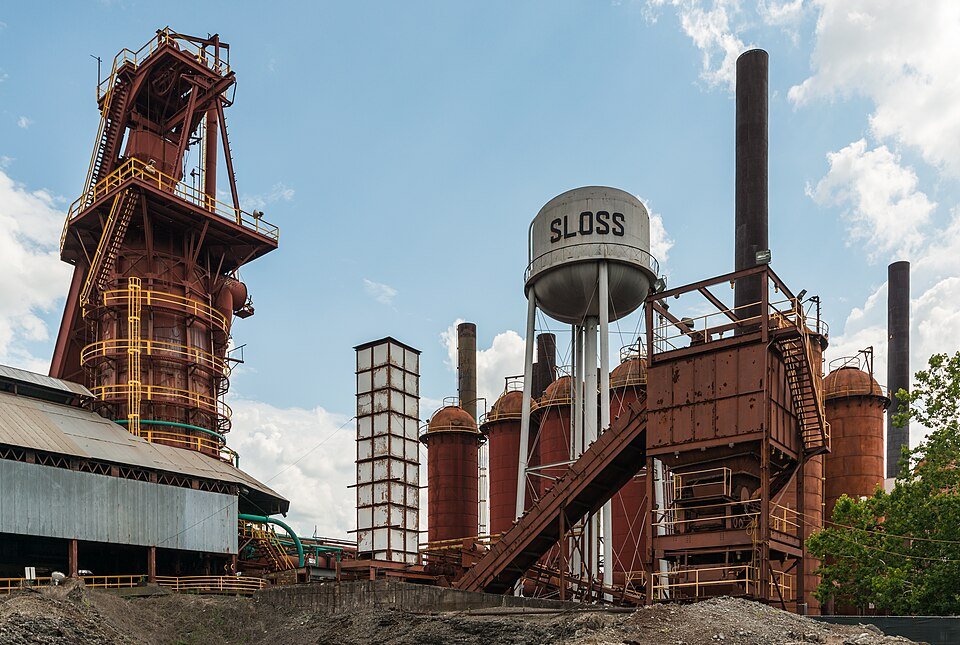 A Sloss Furnaces vista do norte: a torre de um alto-forno, regeneradores cor de ferrugem e a caixa-d'água com o nome Sloss