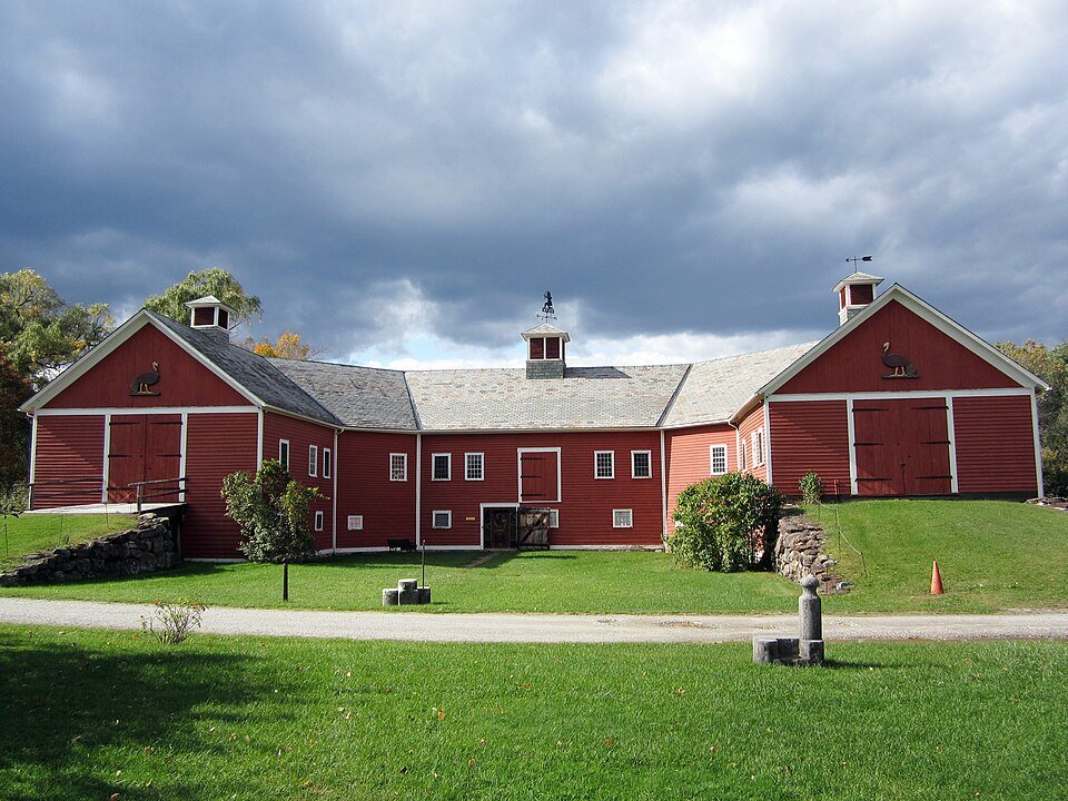 Horseshoe Barn, a long red barn with two gabled wings, under a stormy sky