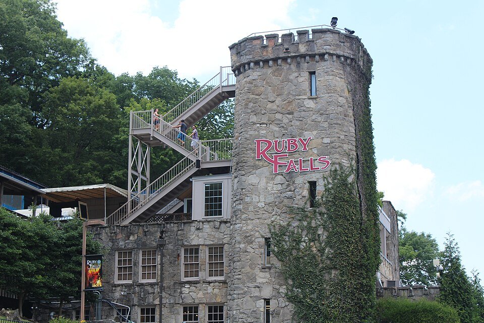 La torre redonda de piedra del edificio de Ruby Falls, con una escalera exterior y el nombre de Ruby Falls en el muro