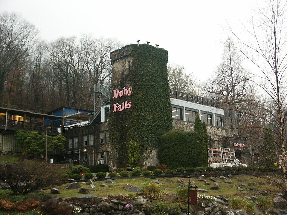 El edificio de piedra de Ruby Falls con una torre cubierta de hiedra y el letrero de Ruby Falls, entre árboles sin hojas