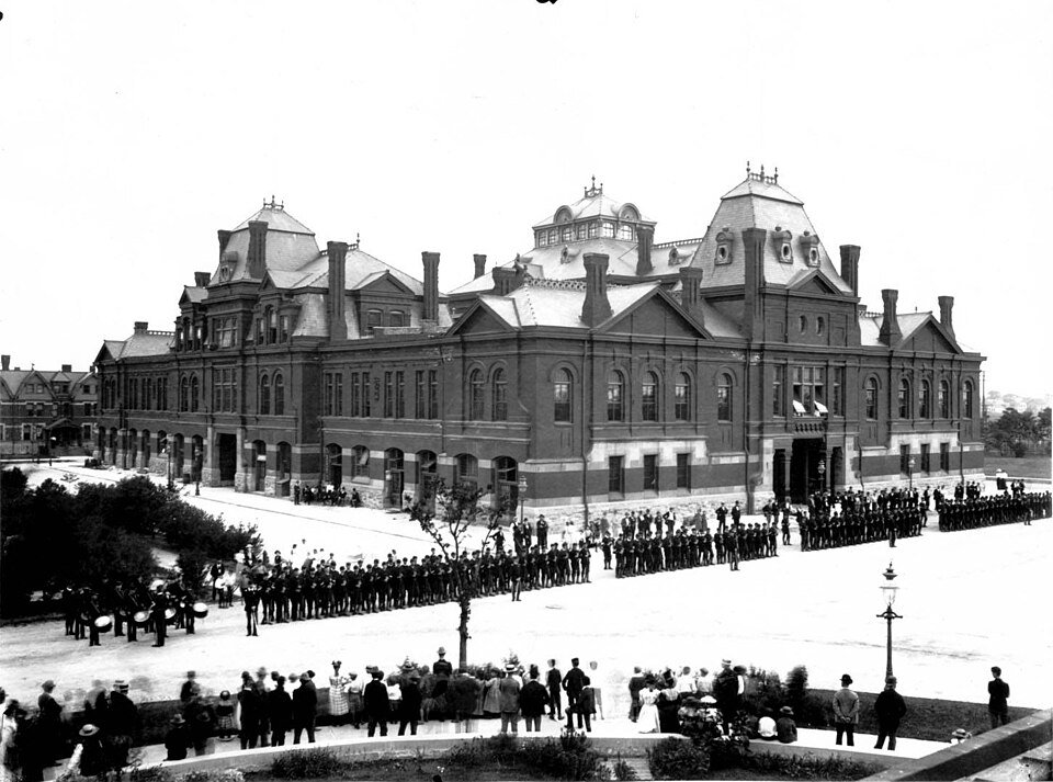 Crowd and rows of uniformed men outside the Arcade Building in Pullman, in a historic photograph