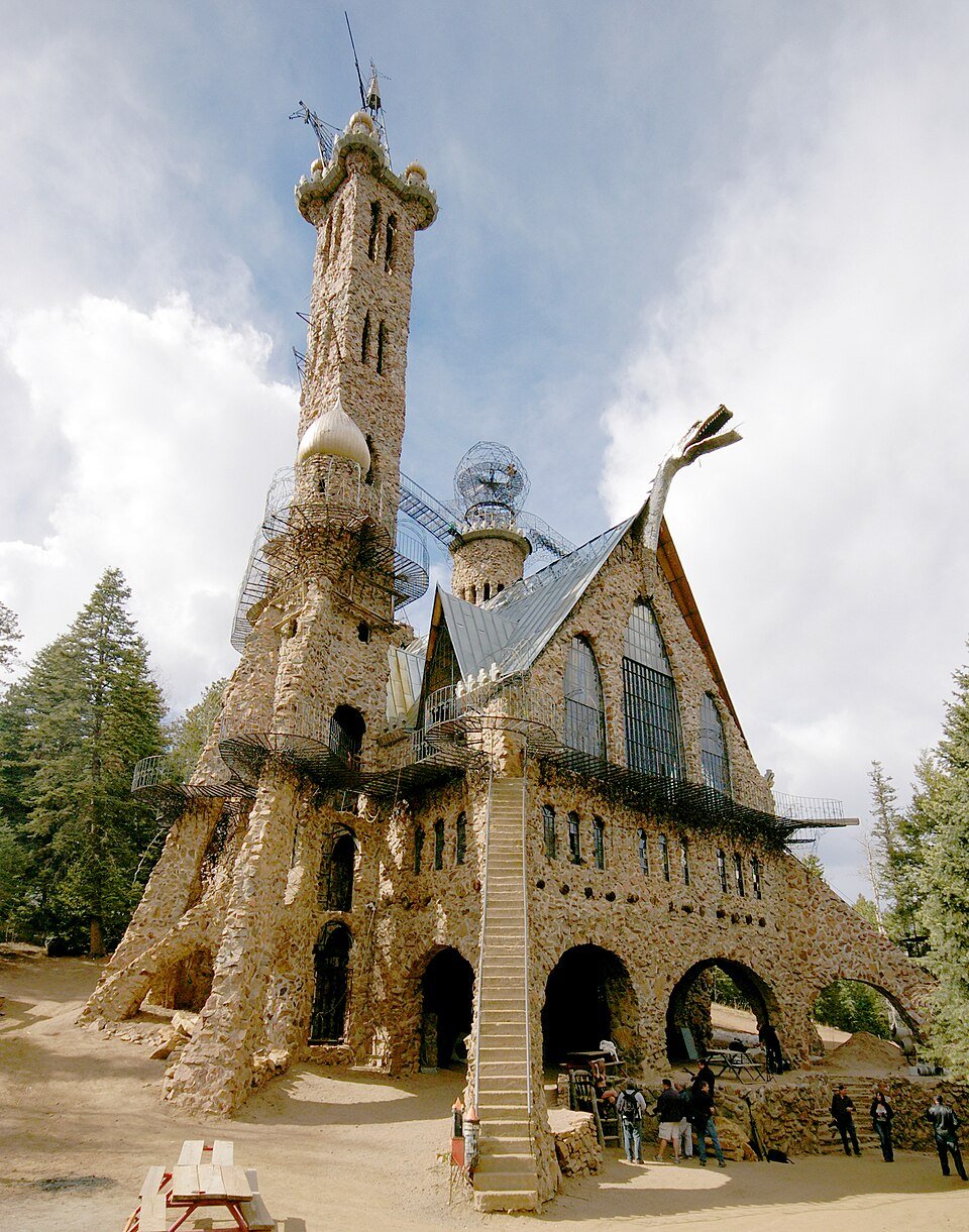 Tall stone tower and gabled hall of Bishop Castle with a central stairway and metal walkways under a cloudy sky
