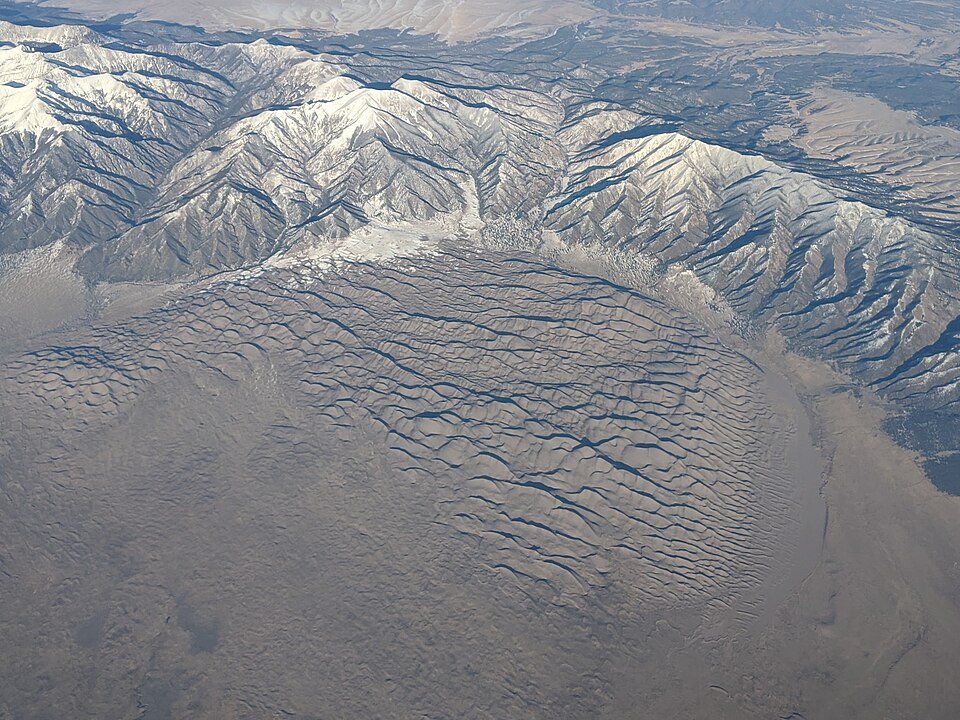 Aerial view of the dune field at the foot of snowy mountains