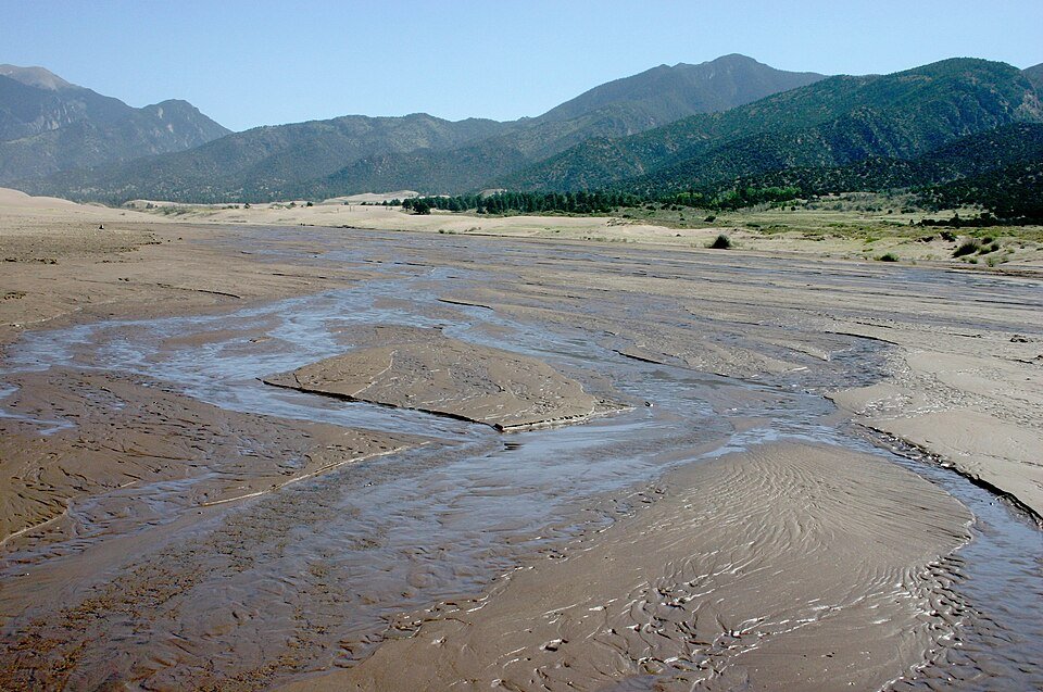 Medano Creek seeping through desert sand at the base of the dunes