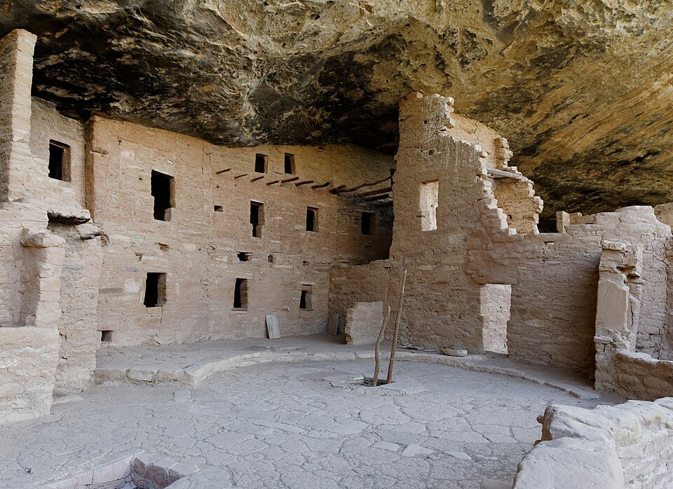 Interior of Spruce Tree House, a cliff dwelling at Mesa Verde, with stone walls, window openings and a circular floor under the overhang