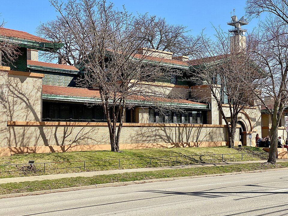 Long brick wall and low roofs of the Dana-Thomas House seen from the street