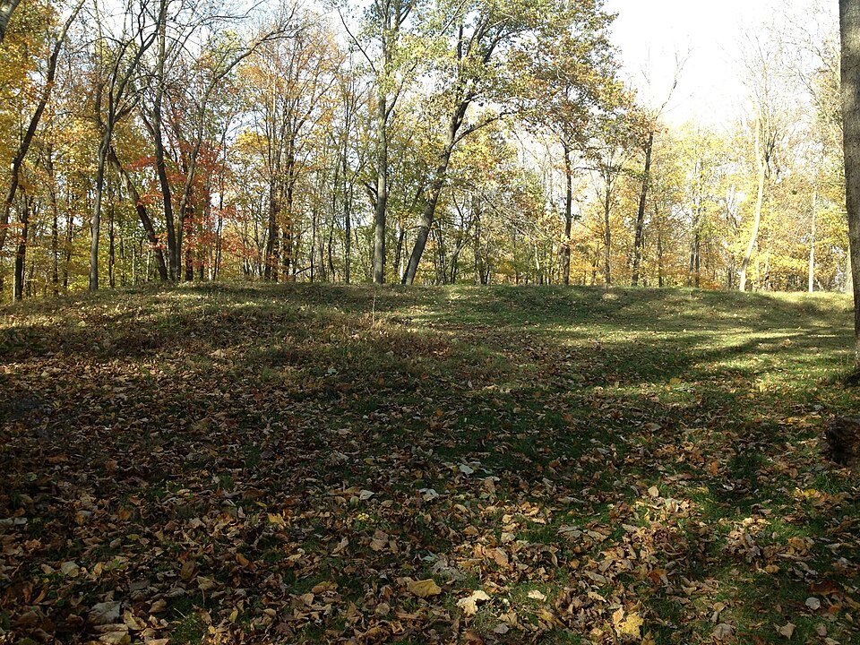 Um montículo coberto de grama entre árvores no outono em Effigy Mounds, Iowa