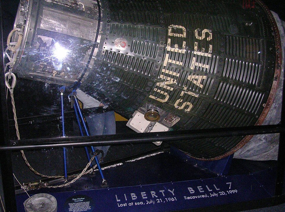 Liberty Bell 7 Mercury spacecraft behind glass, with its recovery dates on the plaque