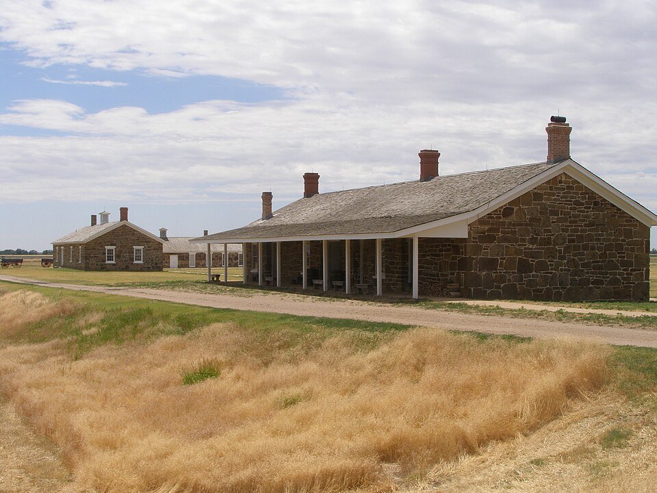 A sandstone commissary building with a long porch at Fort Larned