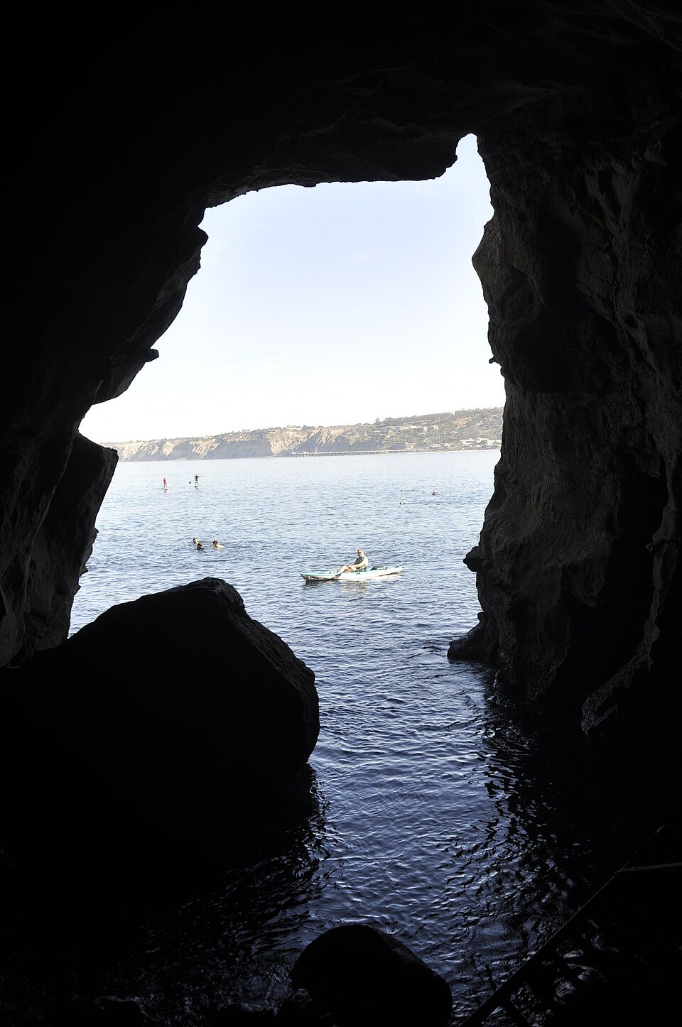 A mesma vista de dentro da caverna, com um caiaquista e nadadores na água