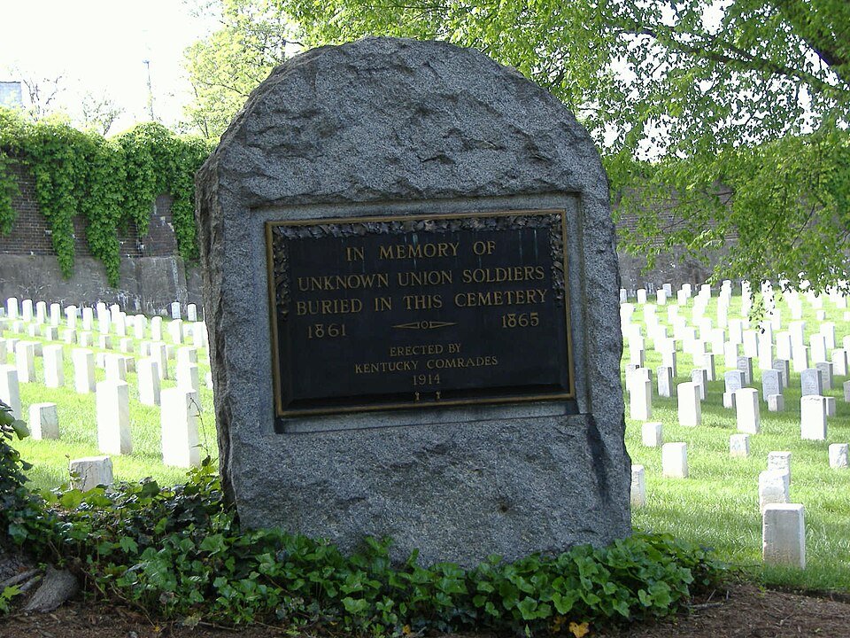 Um monumento a soldados desconhecidos da União entre fileiras de lápides brancas no Cave Hill National Cemetery