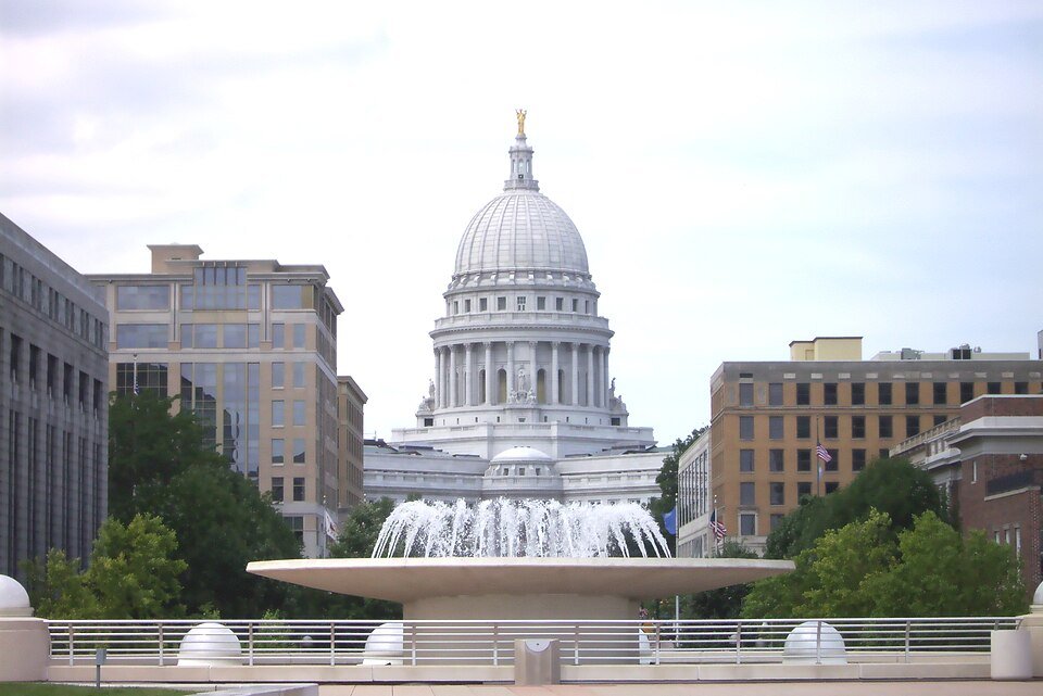 The dome of the Wisconsin State Capitol rising behind a fountain, seen from Monona Terrace