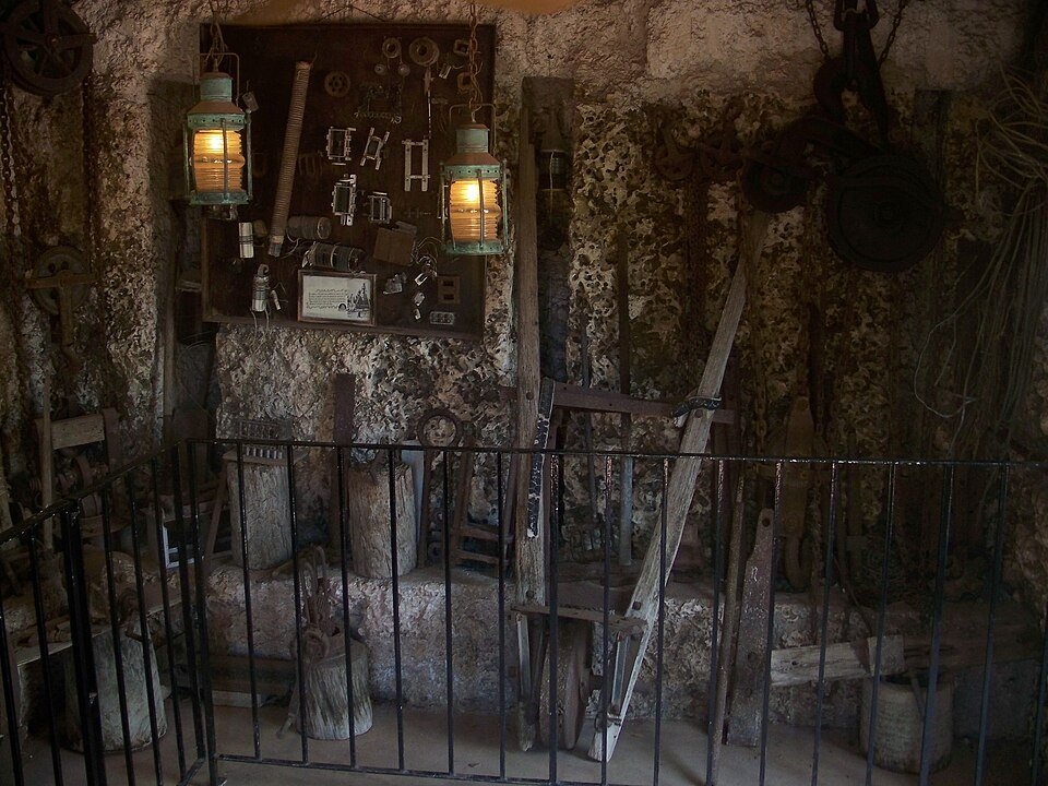 Ferramentas antigas, roldanas e lampiões expostos dentro da torre de Coral Castle