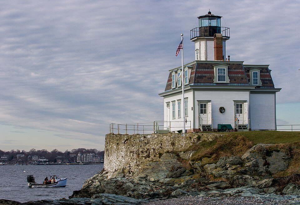 Rose Island Lighthouse, a white keeper's house topped by a lantern tower, on a stone bastion at the water's edge