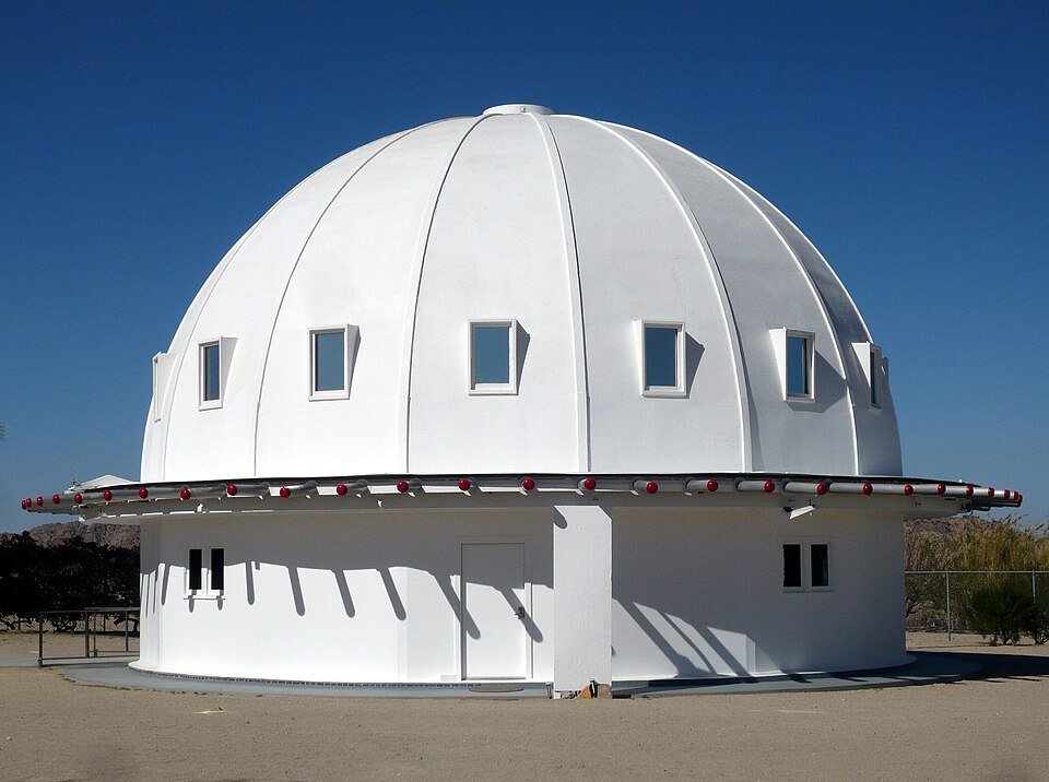 Vista cercana del Integratron, un domo blanco con un anillo de pequeñas luces rojas, en el desierto de Mojave