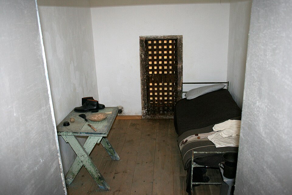 A restored cell with a bed, table and barred door at Eastern State Penitentiary