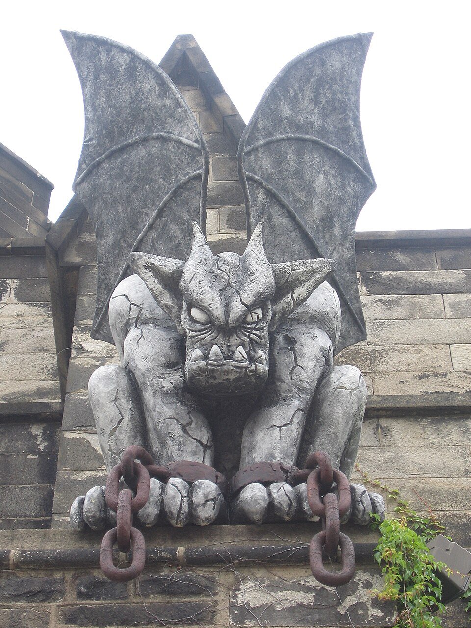 A gargoyle sculpture holding chains on the exterior of Eastern State Penitentiary