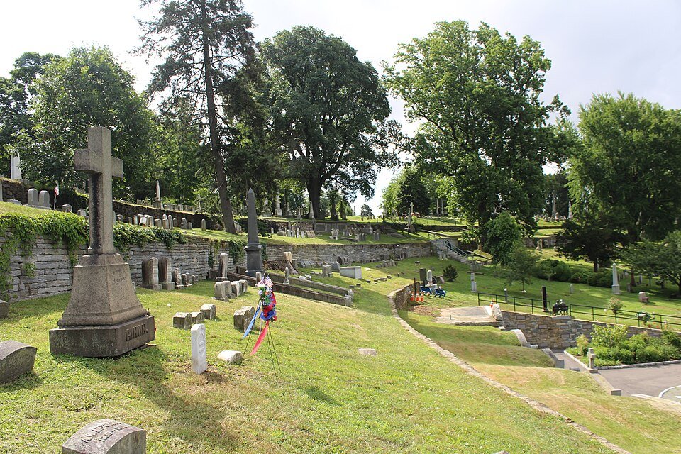 Terrazas de césped con monumentos y árboles antiguos en la sección de la terraza junto al río de Laurel Hill Cemetery