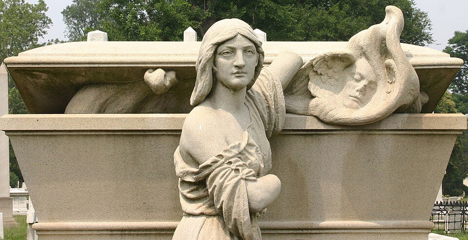 Una figura esculpida en duelo junto a un sarcófago de piedra en Laurel Hill Cemetery