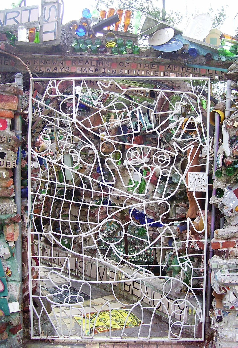 Iron gate of the Magic Gardens on South Street, Philadelphia, with bottles and mosaic behind it