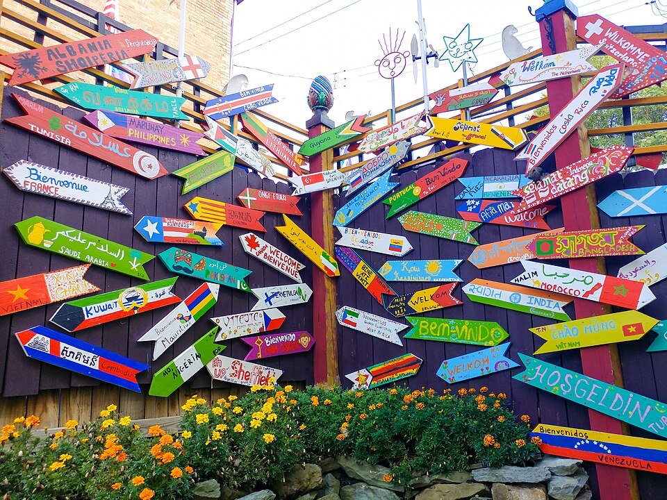 Uma parede de placas de seta pintadas à mão, dando boas-vindas aos visitantes em vários idiomas