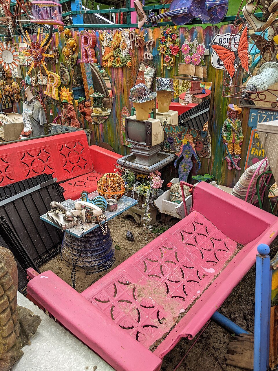 A sala de estar ao ar livre de Randyland, com bancos rosa e vermelhos, uma TV antiga e um telefone de disco
