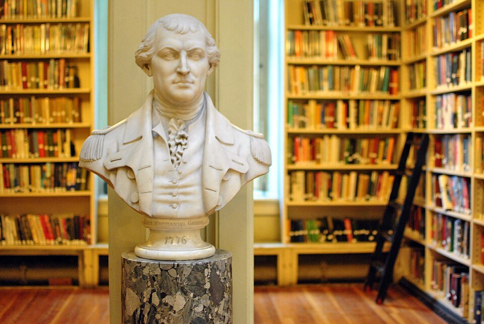Busto de mármol sobre un pedestal de piedra entre las estanterías de la biblioteca