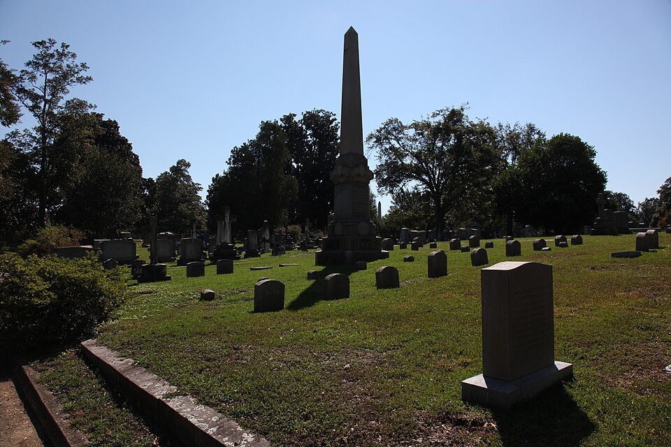 A tall obelisk rising above old graves under a clear sky