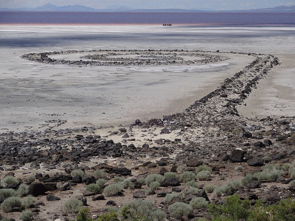 A Spiral Jetty vista da encosta acima, com o lago ao fundo e um pequeno grupo de visitantes na extremidade