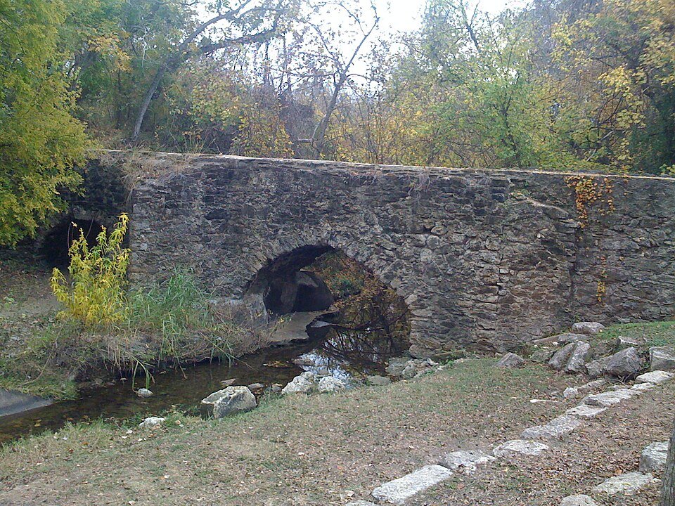 Os arcos de pedra do aqueduto de Espada sobre um riacho, perto da Mission Espada