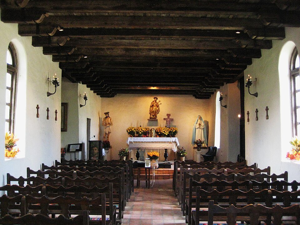 Interior da capela da Mission Espada, com teto de vigas de madeira e um altar