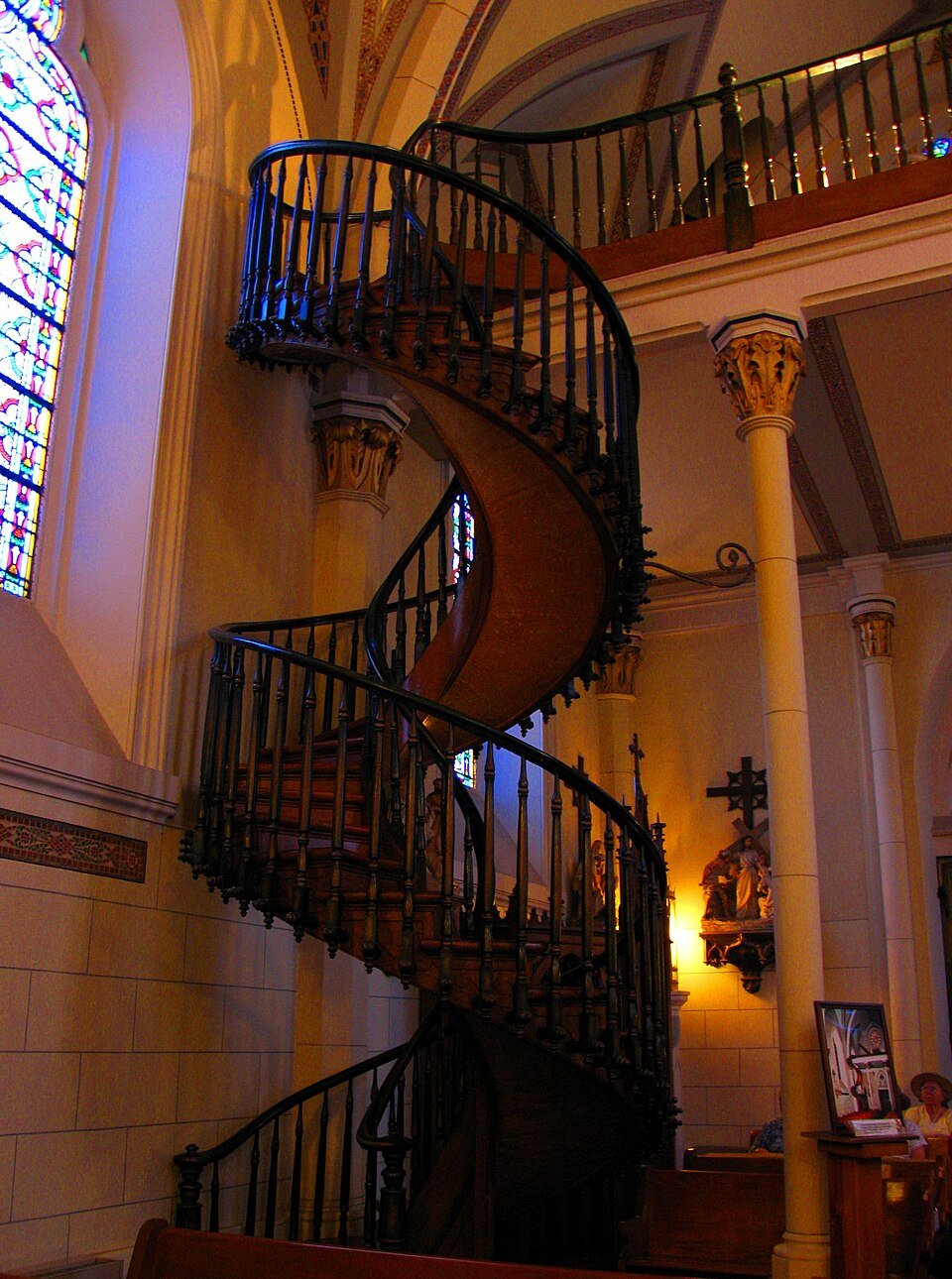 La Escalera Milagrosa con sus barandas curvas junto a un vitral