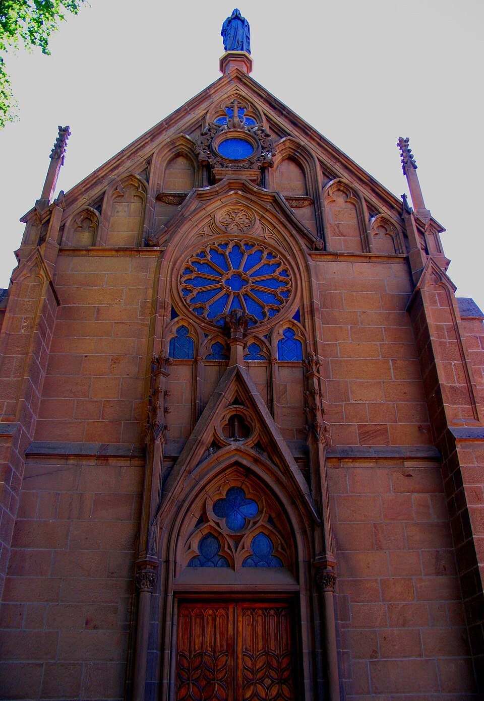 Fachada neogótica de Loretto Chapel con su rosetón y su puerta de madera tallada