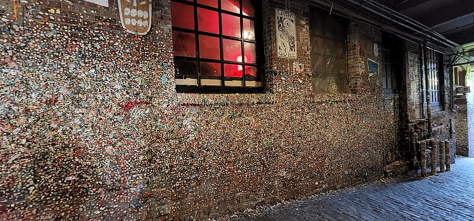 A wide view of the Gum Wall bricks beside a red-lit window, in 2022