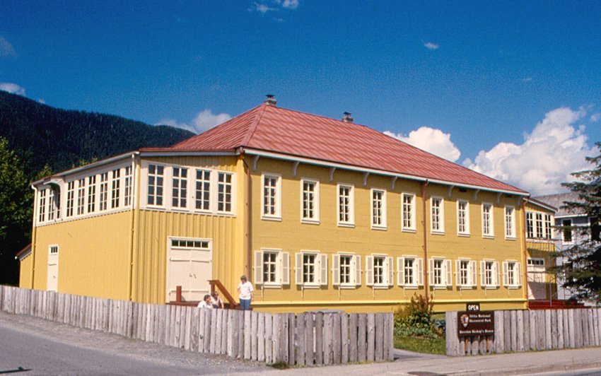 The Russian Bishop’s House on a sunny day, with a wooden fence and a National Park Service sign in front