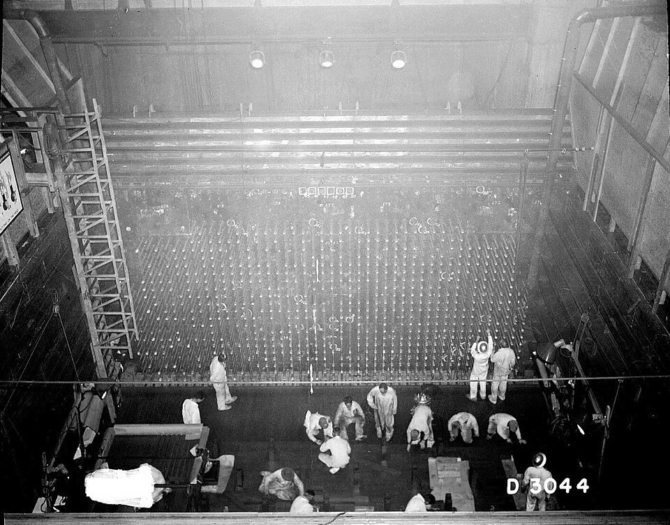 Historic black-and-white photograph of workers at the loading face of the reactor core